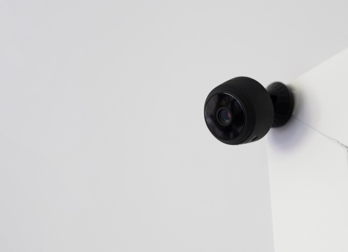 Compact black indoor security camera installed on white wall corner for home surveillance