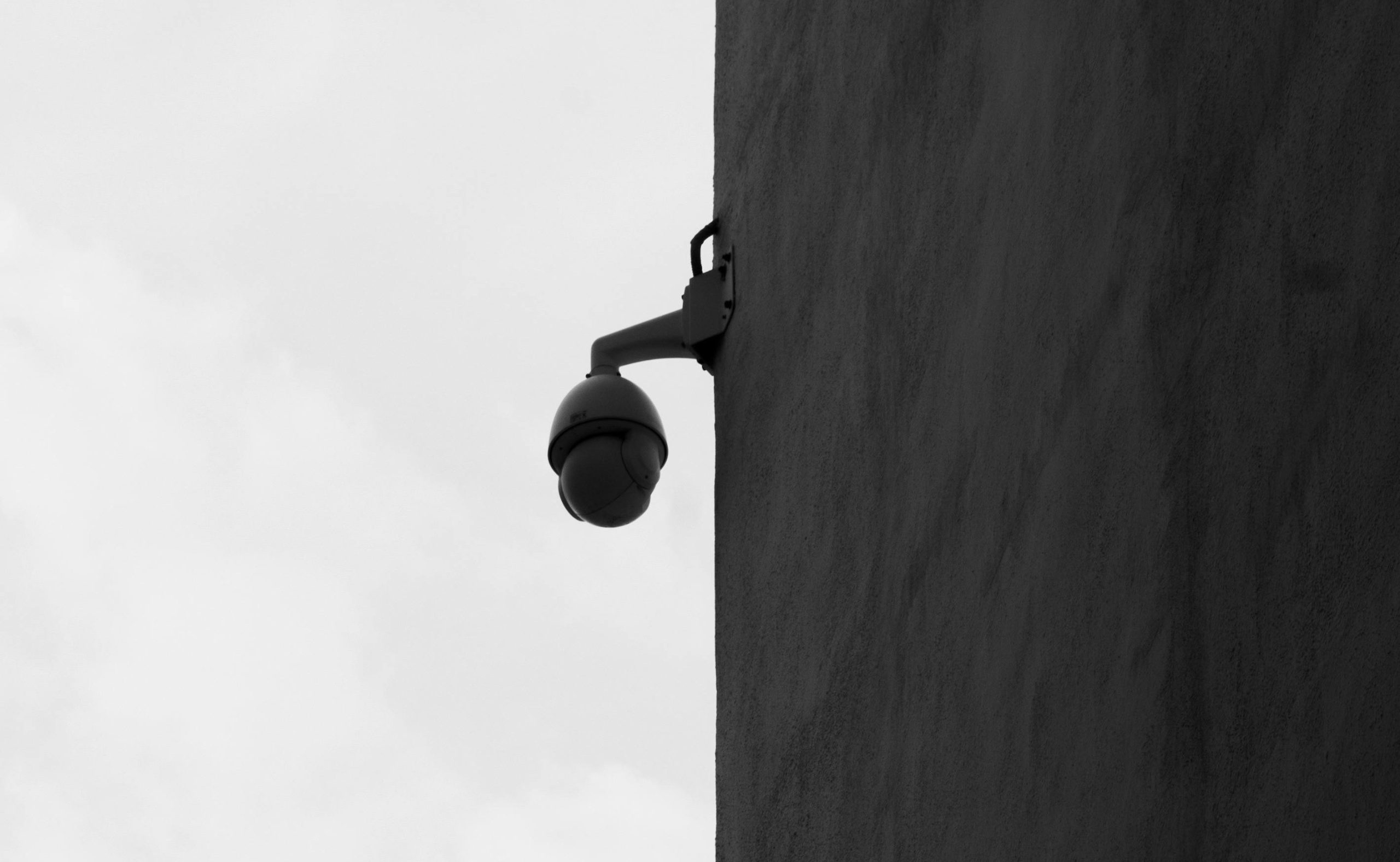 Exterior Commercial Security Camera Dome security camera mounted on a building exterior wall against a gray sky